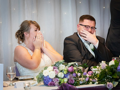 Wedding couple laugh and cover their faces during the best man's speech