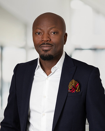 A professional headshot of a man in an office environment