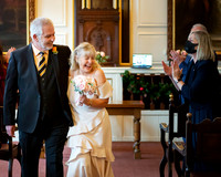 A bride and groom giggle together as they walk out of their ceremony in Windsor Guildhall
