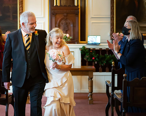 A bride and groom giggle together as they walk out of their ceremony in Windsor Guildhall