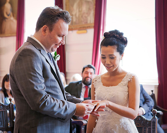 A groom puts his bride's ring on within the Grand Chamber of Windsor Guildhall