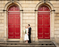 A wedding couple smile at each other in front of Windsor Guildhall's red doors
