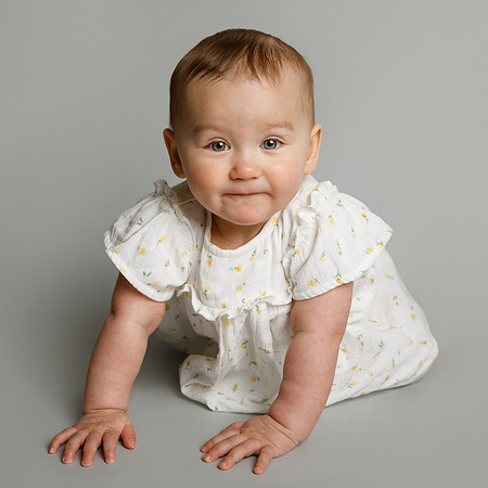 Baby girl crawling towards the camera in a photo studio